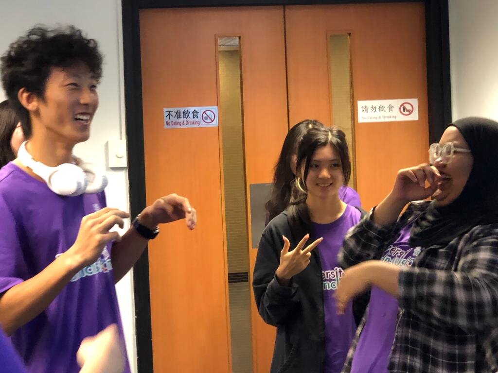 A group of ambassadors wearing purple "Diversity & Inclusion" shirts engage in happy conversation at the D&I Ambassador Programme Opening Ceremony.