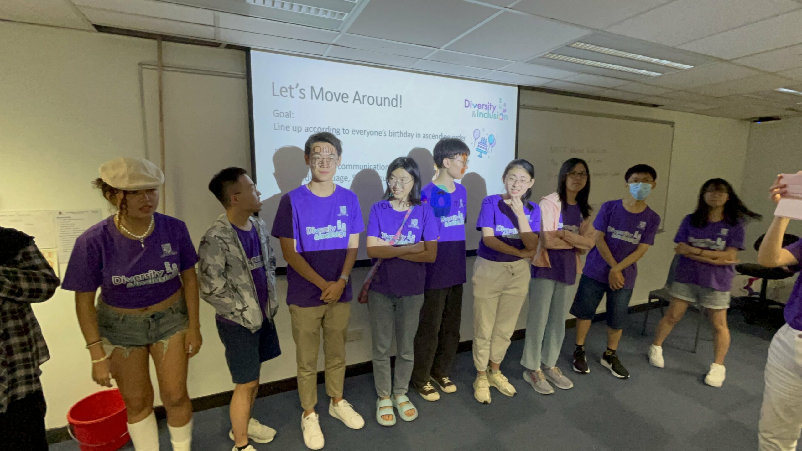 A group of ambassadors wearing purple "Diversity & Inclusion" shirts are engaged in an ice-breaking game at the D&I Ambassador Programme Opening Ceremony.