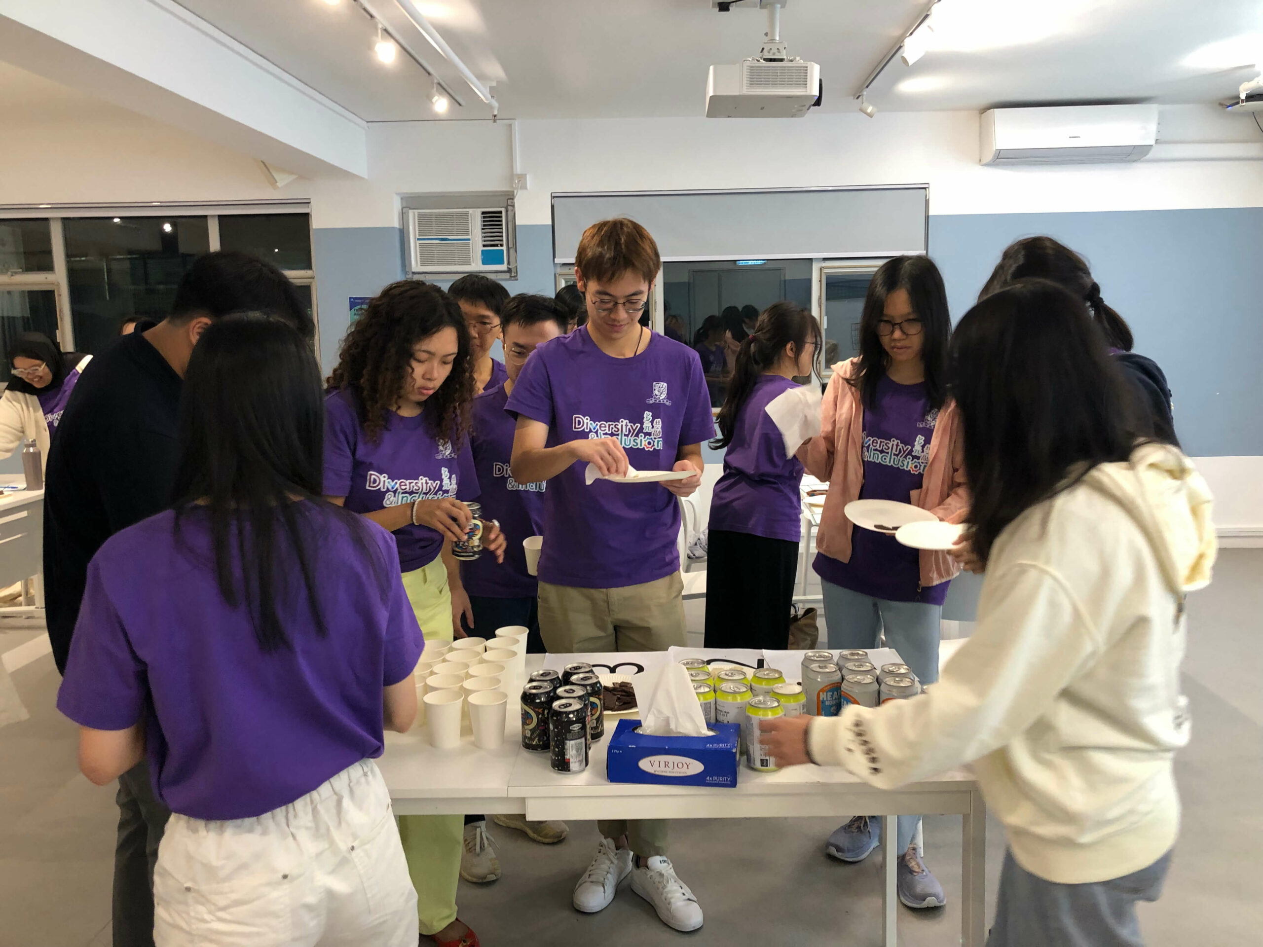 Group of ambassadors in purple shirts serving chocolate and beer indoors during the ‘Beer, Chocolate & Inclusion’ workshop