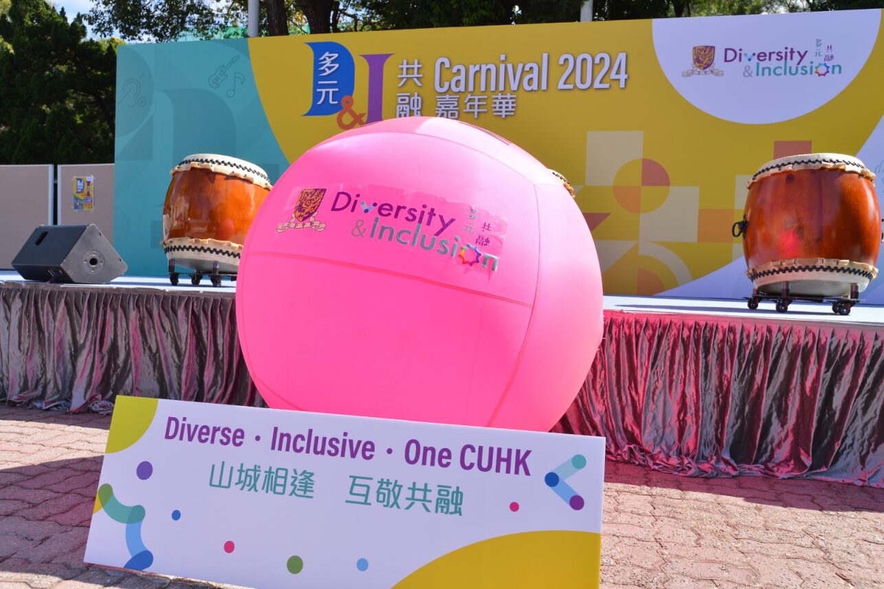 A stage setup with a large pink kin-ball displaying the "Diversity & Inclusion" logo, traditional drums, and a colorful backdrop with the "Carnival 2024" theme.