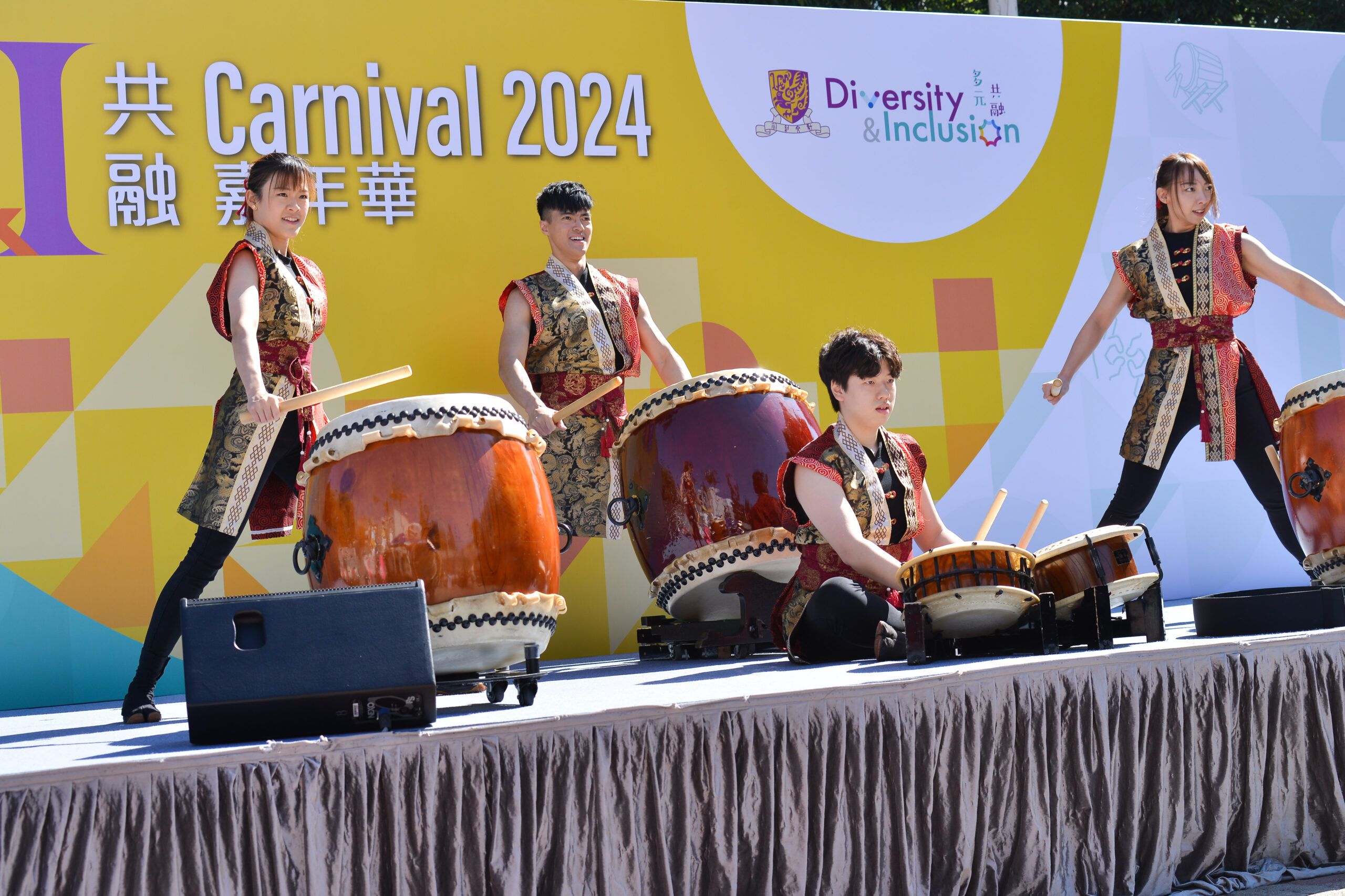 Performers on stage play traditional Japanese taiko drums, wearing traditional attire.