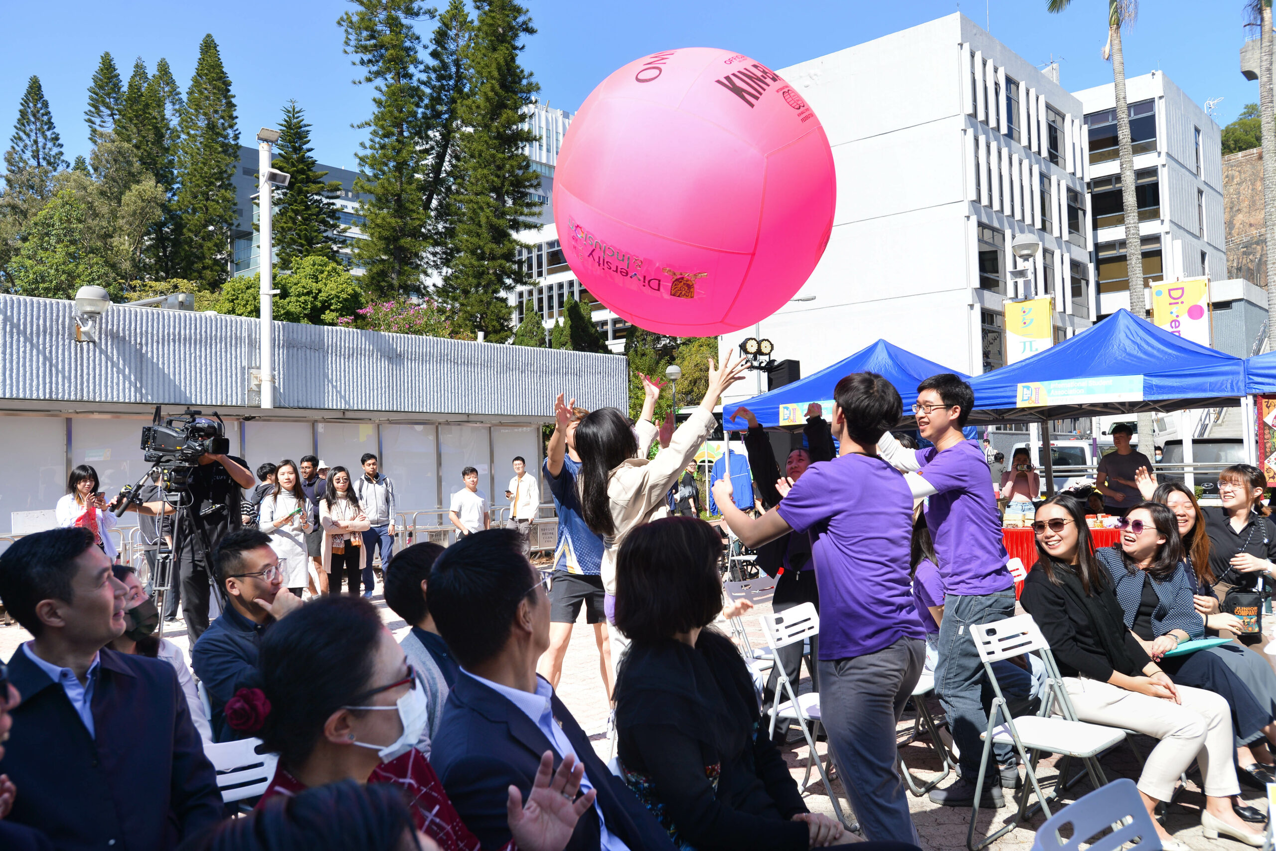 The guests and student ambassadors are reaching towards a large pink Kin-ball.