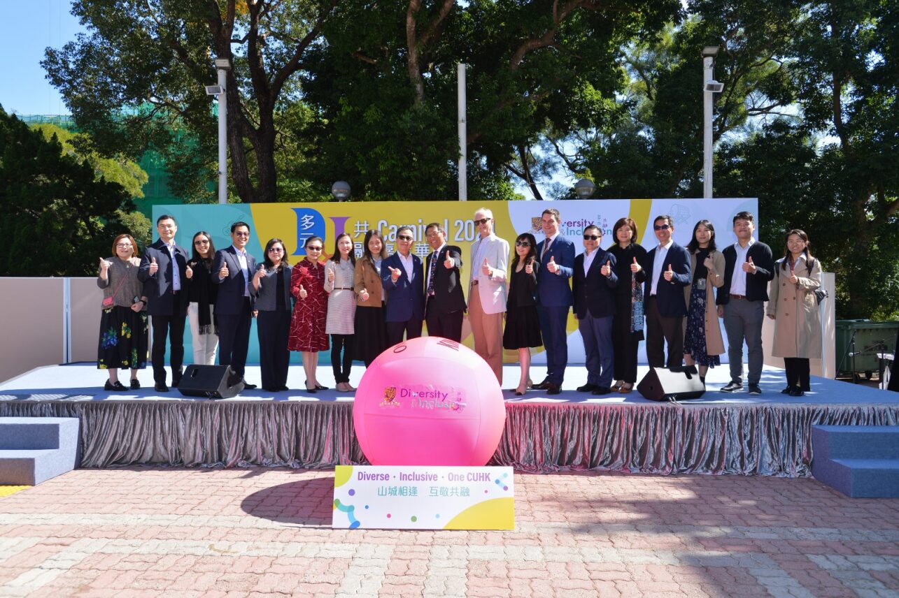 A group of people stands on a stage with a large pink kin-ball displaying "Diversity & Inclusion."