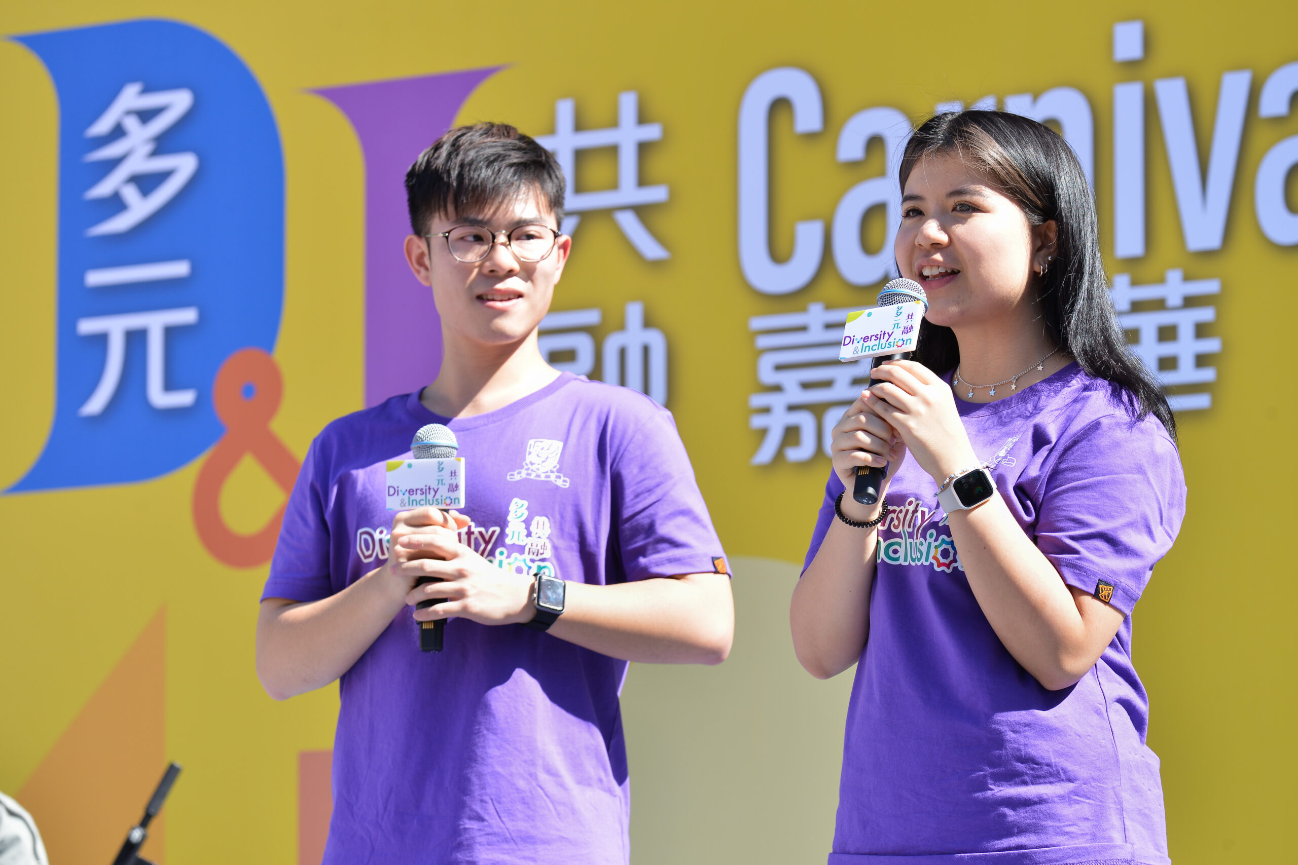 Two ambassadors wearing 'Diversity & Inclusion' shirts speak on stage at D&I Carnival 2024,