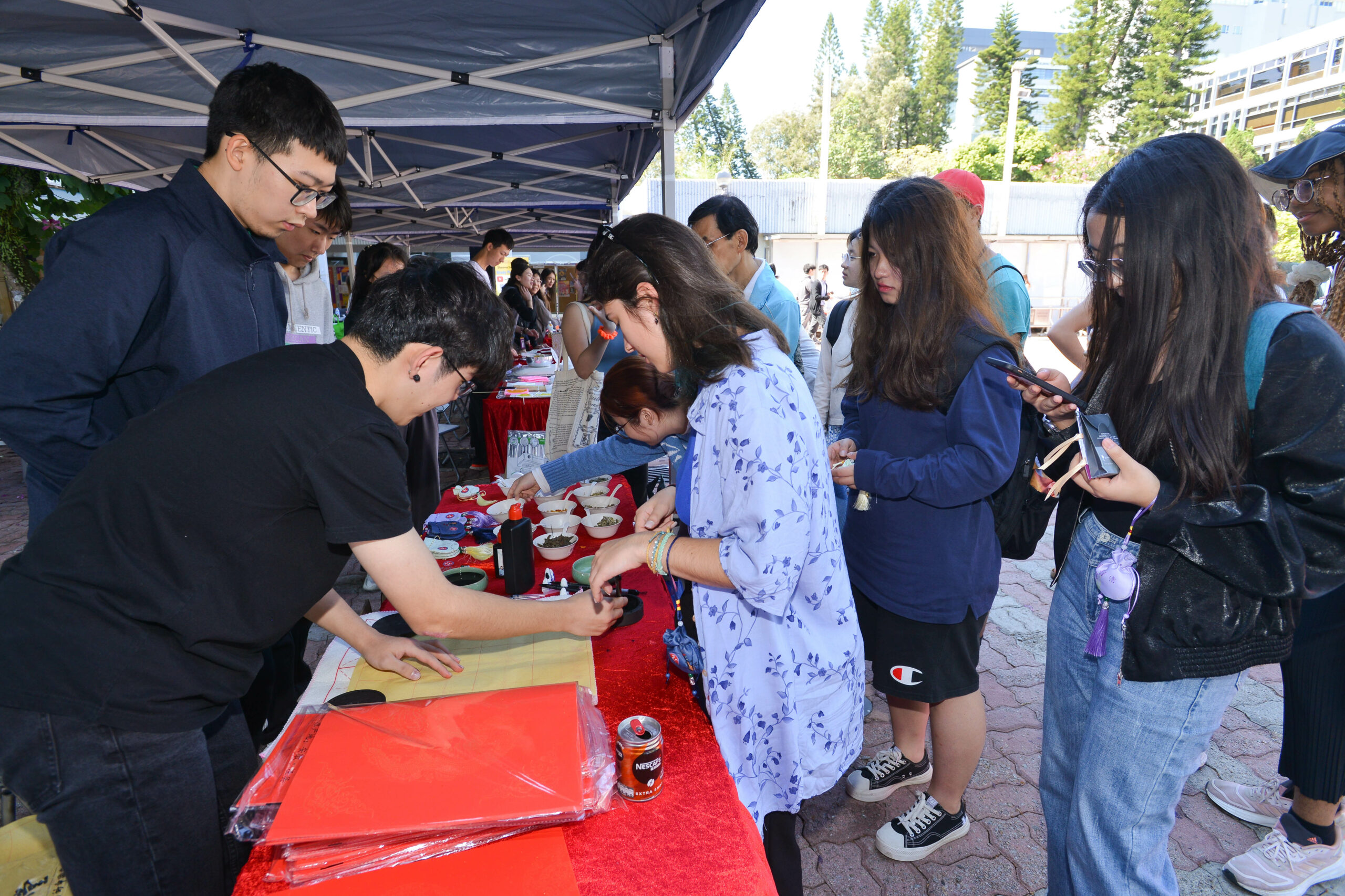 Participants at D&I Carnival 2024 gathered under a canopy tent, writing fai chuns.