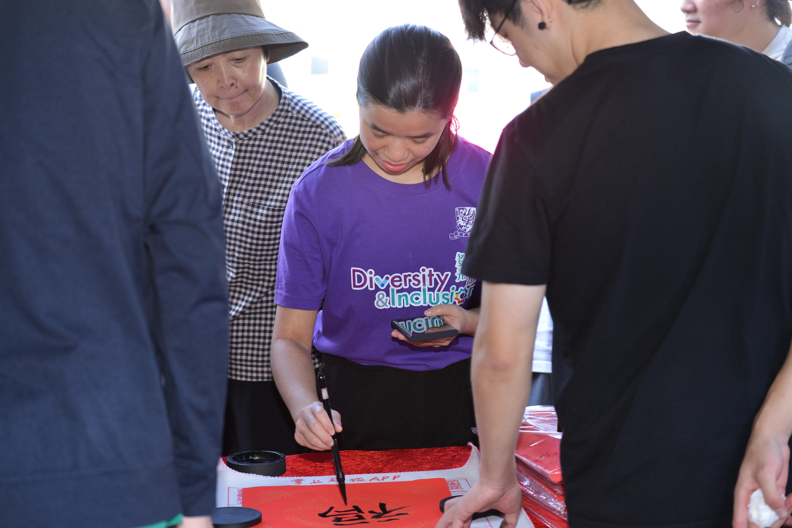 Participants at D&I Carnival 2024 gathered around a table, writing fai chun, promoting diversity and inclusion