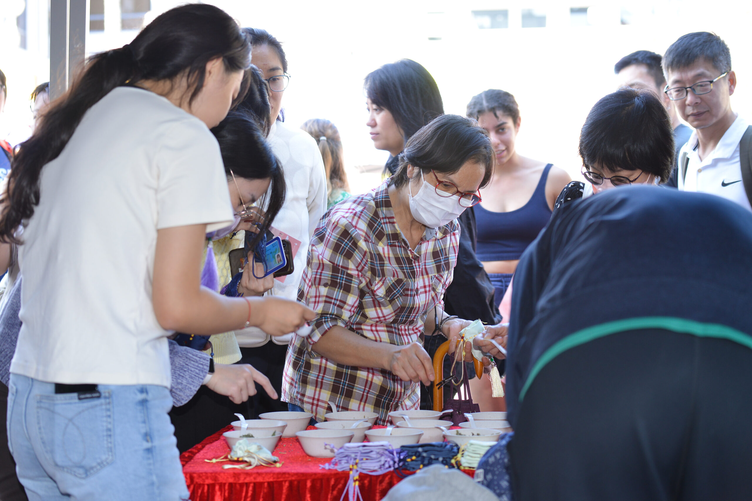 Participants at D&I Carnival 2024 around a table with bowls and items on a red cloth, engaging in a communal activity