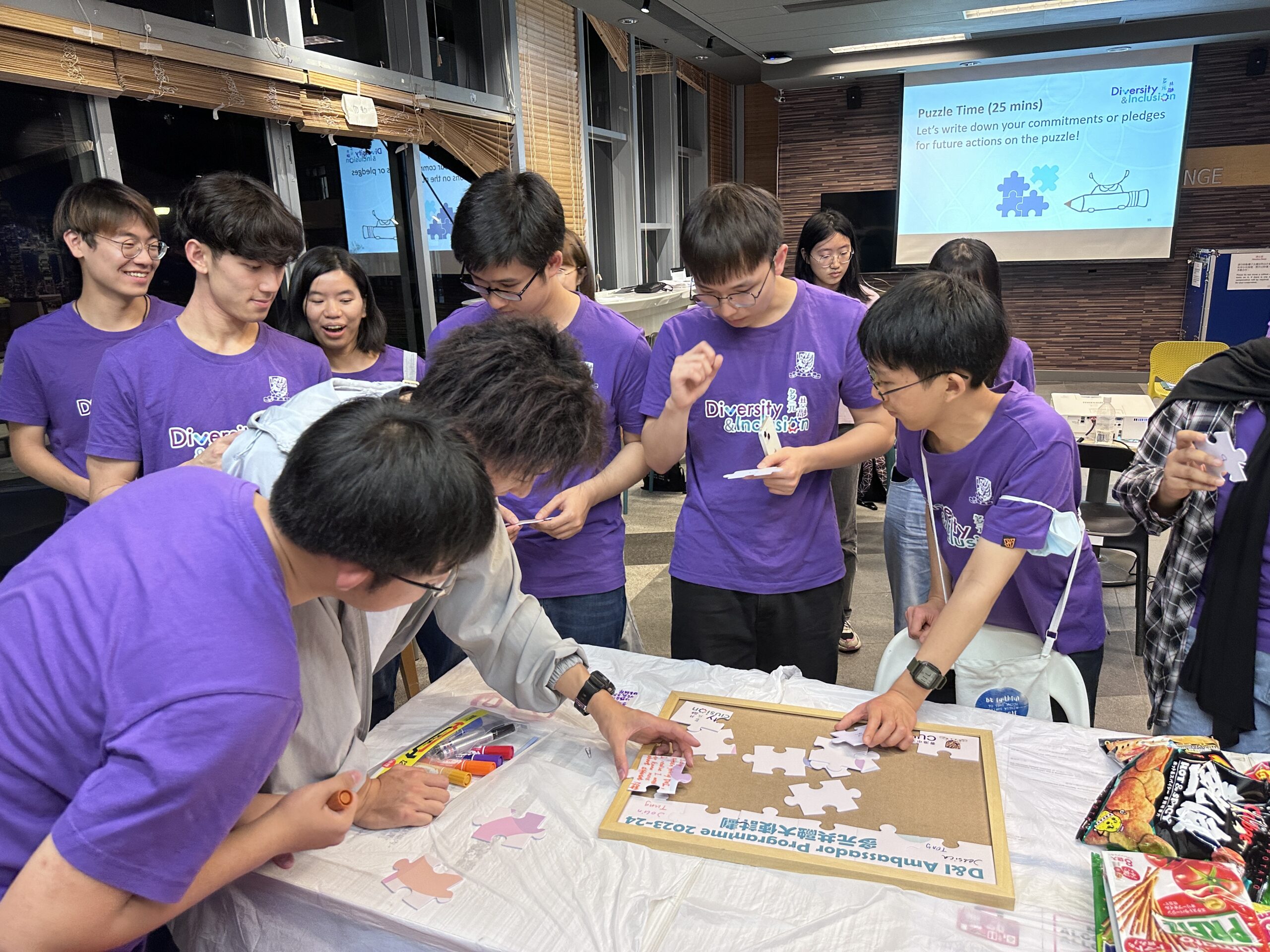 Group of ambassadors engages in an activity involving puzzle pieces around a table. They write down their commitment to diversity and inclusion.