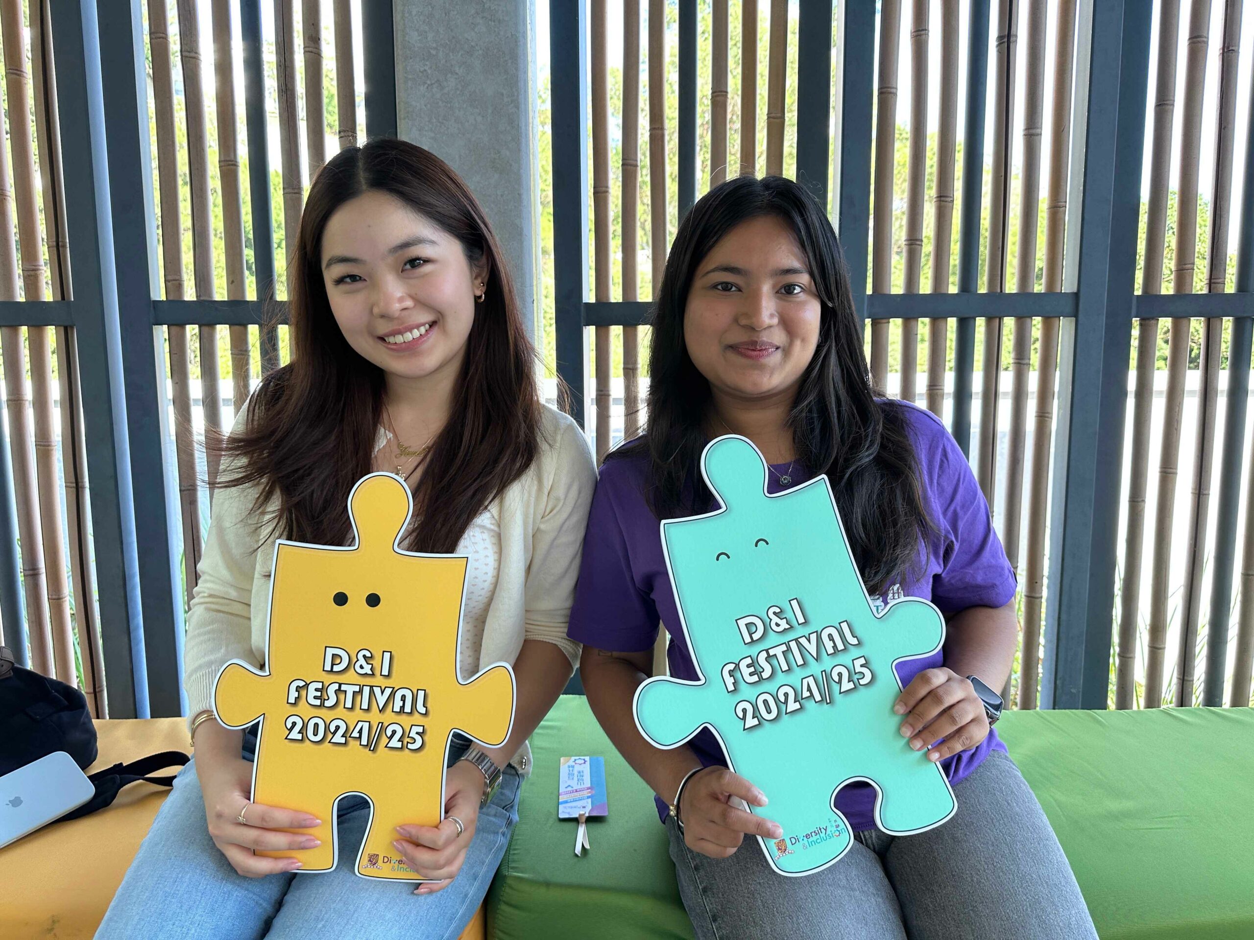 The D&I ambassador and a participant are holding colorful props promoting D&I festivals, smiling.