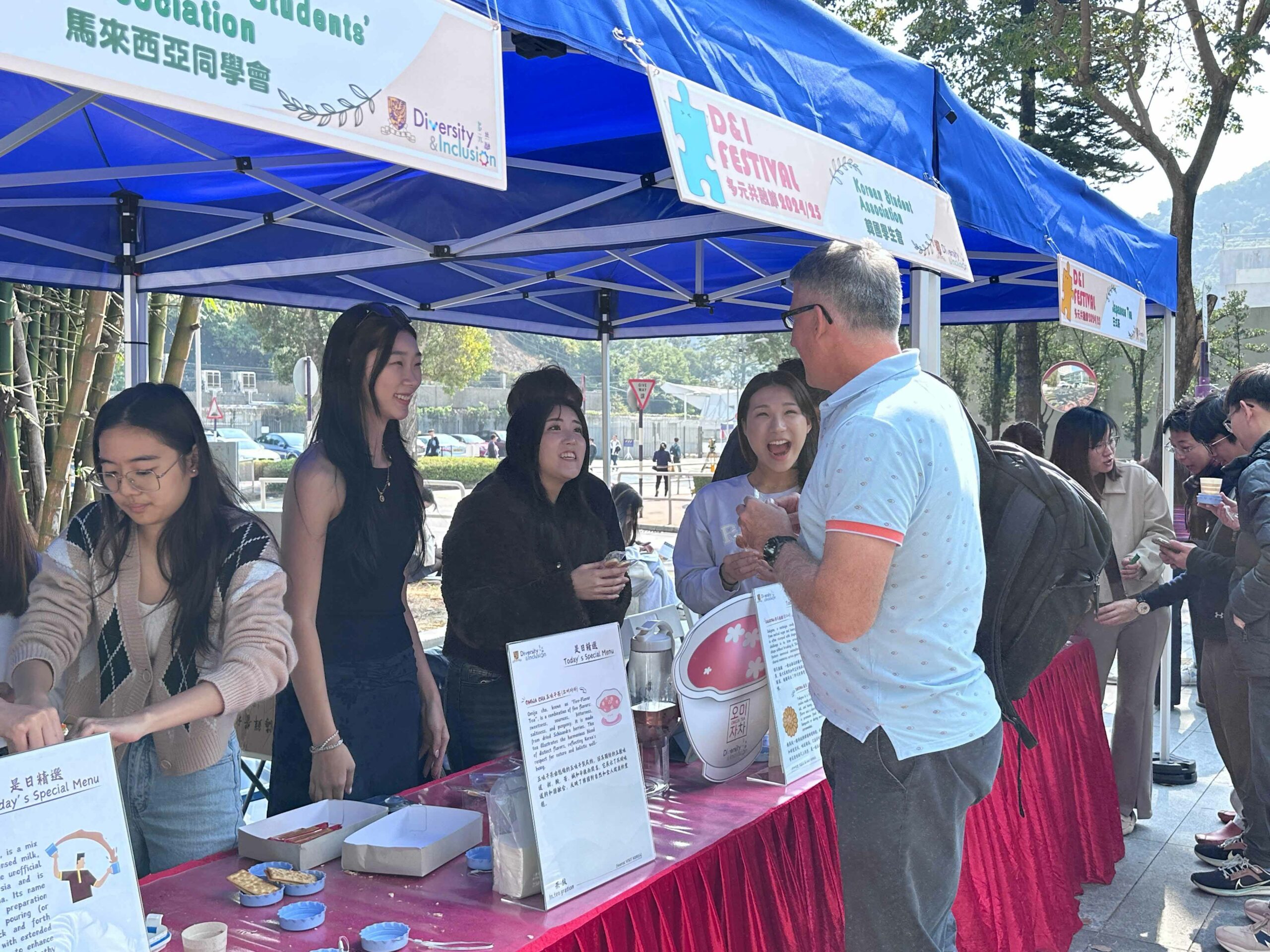 Students from the Korean Student Association are chatting with a participant and smiling.